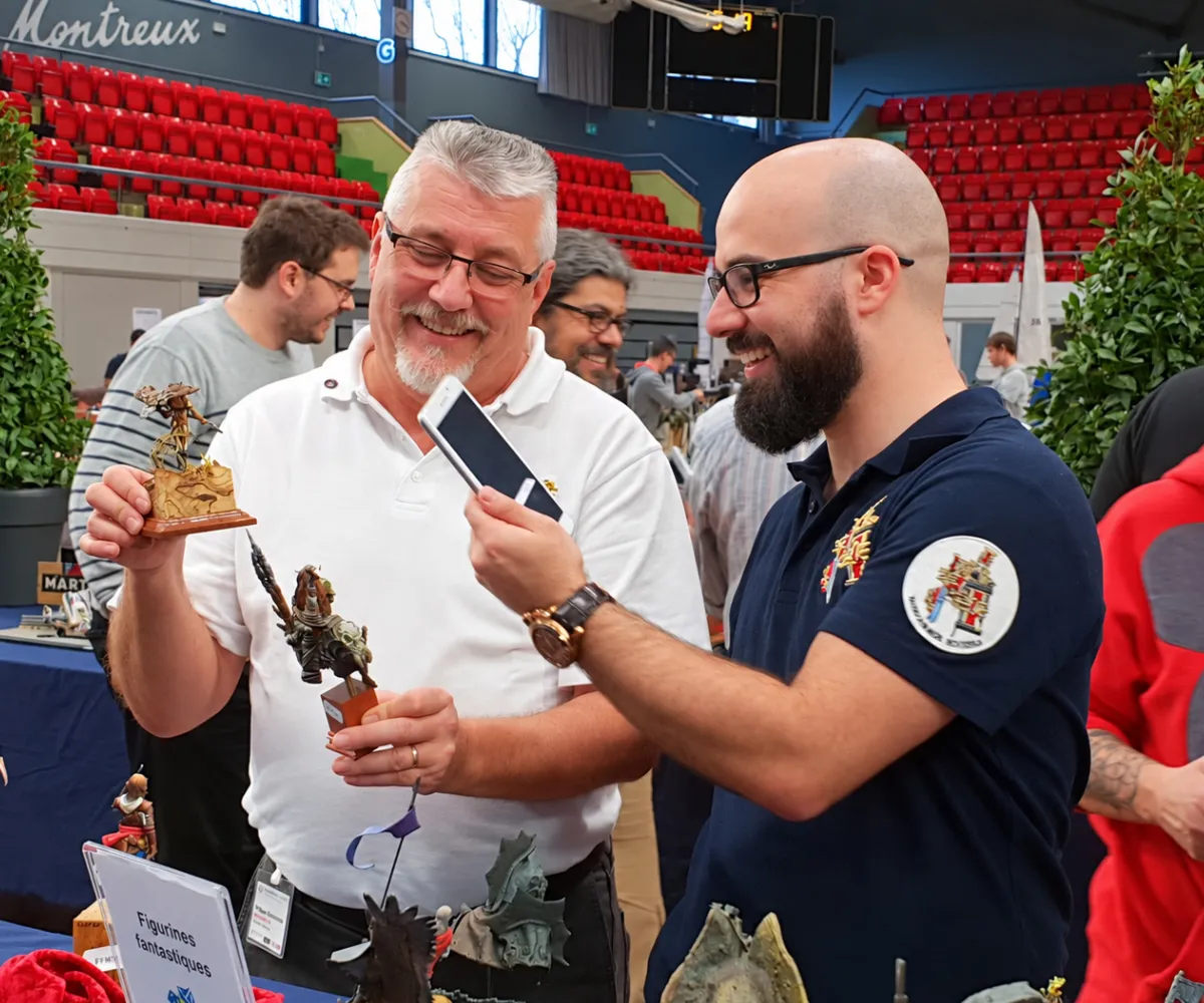 Deux visiteurs souriants photographient des figurines fantastiques